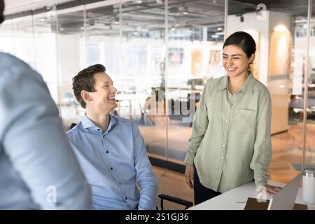 Glückliche junge indische Geschäftsfrau, die mit männlichen Kollegen spricht Stockfoto