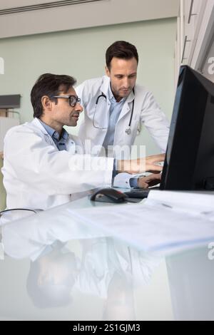 Team von zwei männlichen Ärzten, die den medizinischen Fall am Computer überprüfen Stockfoto