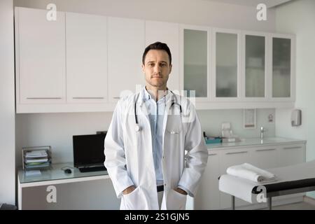 Ernsthaft zuversichtlicher männlicher Arzt, der für Porträt steht Stockfoto