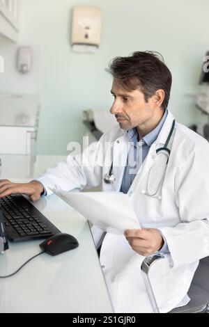 Fokussierter Arzt mittleren Alters, der am Desktop arbeitet Stockfoto