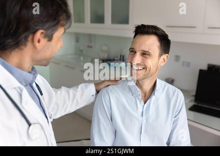 Fröhlicher Patient mit unterstützender Schulterberührungsgeste vom Arzt Stockfoto