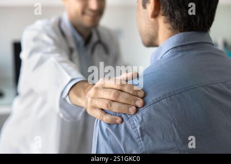 Abgeschnittener Schuss eines positiv sympathischen Arztes, der die Schulter des Menschen berührt Stockfoto