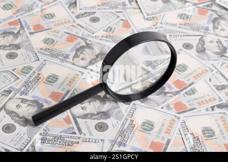 Lupe auf dem Hintergrund eines Dollarbündels auf dem Tisch. Textur US-Dollar. Banknoten. Amerikanisches Geld Stockfoto