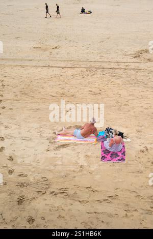 Ein reifes Urlaubspaar, das sich am Towan Beach in Newquay in Cornwall in Großbritannien entspannt. Stockfoto