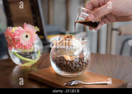 Ein entzückendes Affogato in einer einzigartigen Glasschale gefüllt mit Kaffeebohnen. Mit einer cremigen Portion Vanilleeis, garniert mit zerkleinerten Nüssen Stockfoto