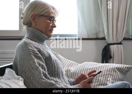 Seniorin, die auf ihrem Smartphone Online-Shops durchsucht Stockfoto