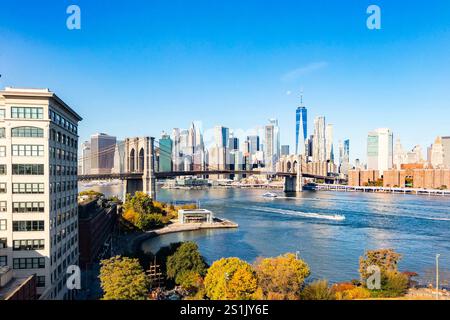 Malerischer Blick auf die Brooklyn Bridge und die Skyline von Manhattan an einem klaren Tag mit dem East River im Vordergrund Stockfoto