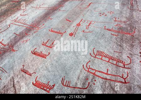 Die Rote Malerei der Tanum-Felsritzereien auf dem Vitlycke-Flachfelsen zeigt Boote, Menschen und Tiere aus der Bronze- und Eisenzeit. Stockfoto