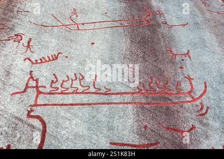 Die Rote Malerei der Tanum-Felsritzereien auf dem Vitlycke-Flachfelsen zeigt Boote, Menschen und Tiere aus der Bronze- und Eisenzeit. Stockfoto