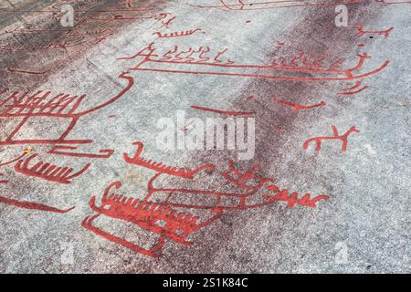 Die Rote Malerei der Tanum-Felsritzereien auf dem Vitlycke-Flachfelsen zeigt Boote, Menschen und Tiere aus der Bronze- und Eisenzeit. Stockfoto