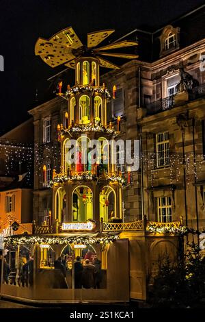 Speyer, Deutschland, 28.12.2023: Weihnachtsmarkt mit beleuchteter großer Weihnachtspyramide, Feuerzangenbowle ist ein deutsches alkoholisches Wintergetränk Stockfoto