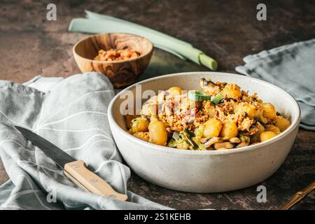 Gnocchi in einer cremigen Pilzsauce mit Frühlingszwiebeln und knusprigem Brotkrumenbelag, rustikaler Holzhintergrund Stockfoto
