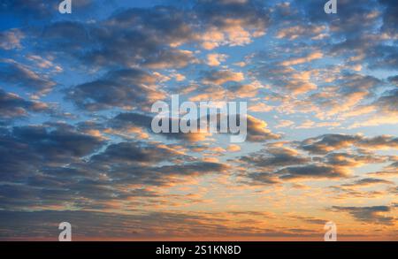 Wunderschöne bunte flauschige Wolken und warmer Sonnenaufgang glänzt am blauen Himmel Stockfoto
