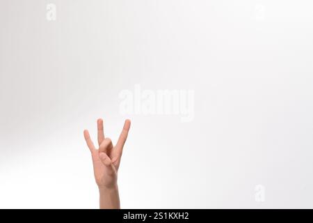Eine Nahaufnahme einer Hand, die eine bestimmte Geste vor einem weißen Hintergrund zeigt. Das Bild ist einfach und sauber und konzentriert sich ganz auf das der Hand Stockfoto