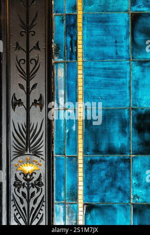 Nahaufnahme von türkisfarbenen Keramikfliesen und verzierten, geschnitzten Türrahmen von Narcissus Hall, Leighton House, London, England Stockfoto