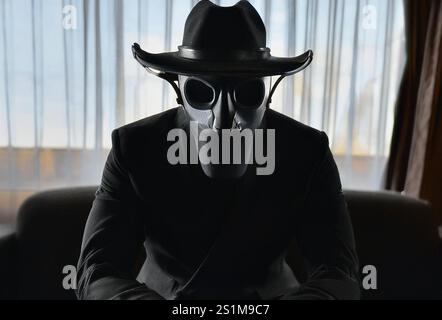Ein zeitreisender Attentäter mit einer Gateway-Maske sitzt in einem Hotelzimmer. Stockfoto
