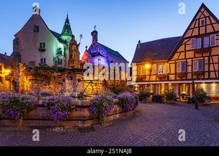 Der Hauptplatz des Feudaldorfes Eguisheim mit Fachwerkhäusern, einem alten Brunnen und einer Kirche. Foto am 10. August 2019 im Stockfoto