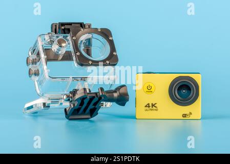 Moskau, Russland - 3. Januar 2025: Gelbe Action-Kamera und transparentes wasserdichtes Gehäuse auf blauem Hintergrund. Konzept der Aufnahme von Unterwasseraufnahmen A Stockfoto