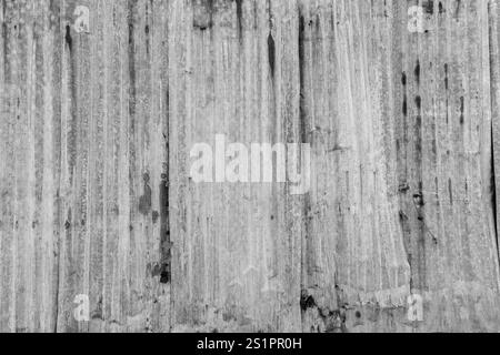 Vorderansicht der Baustellenwand aus rostigem und gewelltem Metall. Abstrakter, strukturierter Hintergrund im Vollformat in Schwarzweiß mit Kopierraum. Stockfoto