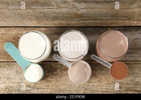 Verschiedene leckere Proteincocktails in Gläsern und Pudern auf Holztisch, flach gelegt Stockfoto
