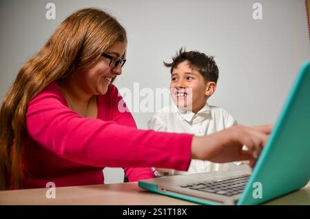 Lächelnde Geschwister, die ein Notebook für Online-Schulungen nutzen und zu Hause gemeinsam lernen Stockfoto