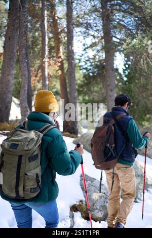 Junges, nicht erkennbares Paar, das auf einem verschneiten Berg wandert und das Winterabenteuer genießt. Stockfoto