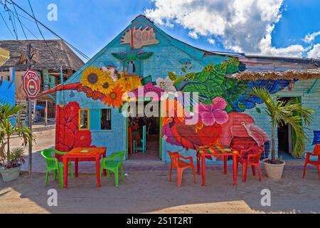 Farbenfrohes Café im Freien mit lebendigen Kunstwerken und rustikalem Dekor an einem sonnigen Tag, Isla Holbox, Mexiko Stockfoto