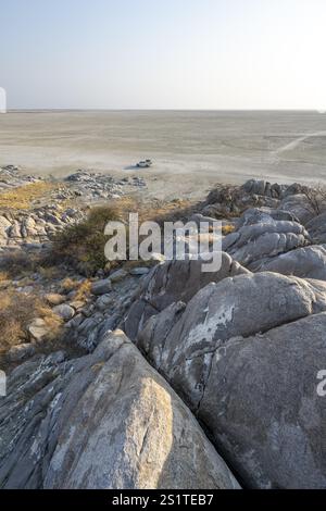 Blick über runde Felsen von Kubu Island (Lekubu) zur Salzpfanne mit Geländewagen, bei Sonnenaufgang Sowa Pan, Makgadikgadi Salzpfannen, Botswana, Afrika Stockfoto