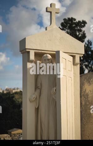 Skulptur von Jesus, der die Tür zum Himmel öffnet, auf einem Grabstein auf einem Friedhof in der Nähe von Valetta, Malta Stockfoto