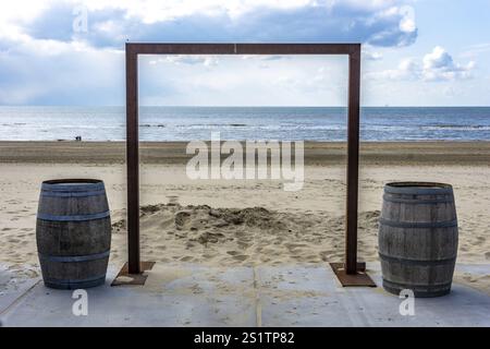 Kunstobjekt am Strand in Holland, ein Holztor mit Blick auf den Sand und das Meer. Art Gate am Meer mit Sandstrand und Wasser Stockfoto