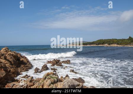 Malerische Aussicht auf Wellen, die an einem schönen sonnigen Tag entlang der Küste sardiniens gegen Felsen prallen Stockfoto