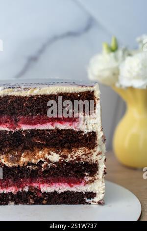 Makroaufnahme von reichhaltigem Schokoladenkuchen mit Schichten Sahnezuckerung Stockfoto