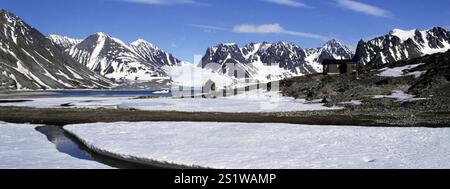 Landschaft am Magdalenefjord mit schneebedeckten, zerklüfteten Bergen. Schneefelder mit Schmelzwasserkanälen im Vordergrund. Heller Sonnenschein, blauer Himmel, c Stockfoto
