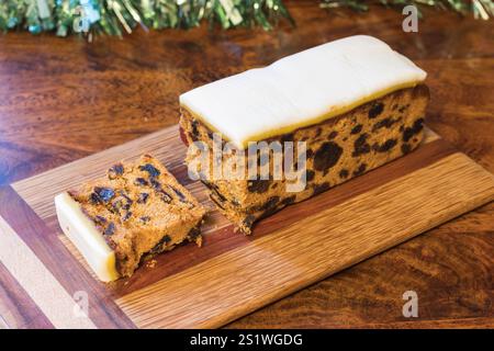 Luxuriöser Iced Rich Fruit Cake mit Brandy, voller Kuchen und Scheibe auf Holzbrett Stockfoto