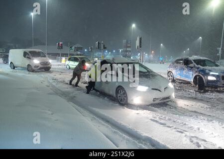 Leute helfen, Autos im Schnee in Leeds, Yorkshire, zu schieben. Starker nächtlicher Schnee sorgt für Störungen in ganz Großbritannien, da der Kaltstart ins neue Jahr anhält. Bilddatum: Sonntag, 5. Januar 2025. Stockfoto