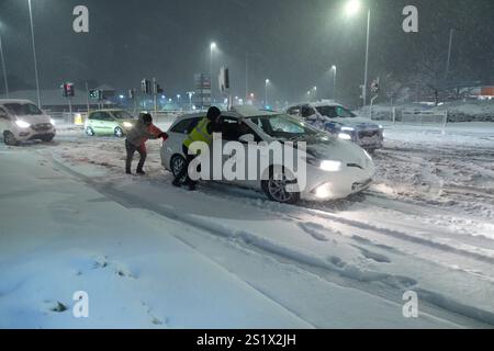 Leute helfen, Autos im Schnee in Leeds, Yorkshire, zu schieben. Starker nächtlicher Schnee sorgt für Störungen in ganz Großbritannien, da der Kaltstart ins neue Jahr anhält. Bilddatum: Sonntag, 5. Januar 2025. Stockfoto
