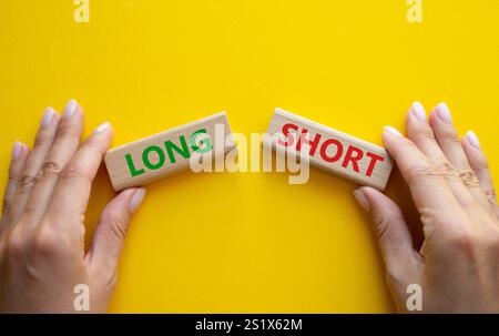 Symbol kurz vs lang. Konzeptwort kurz vs lang auf Holzblöcken. Geschäftsmann Hand. Schöner gelber Hintergrund. Business und kurz- vs Langkonzept. Stockfoto
