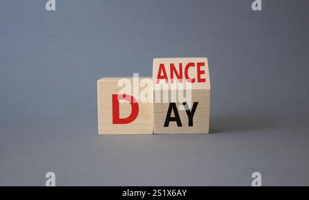 Symbol für den Internationalen Tanztag. Gedrehte Holzwürfel mit den Worten Tanztag. Schöner grauer Hintergrund. Konzept des internationalen Tanztages. Kopierbereich. Stockfoto
