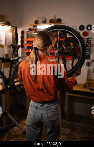 Die junge Frau arbeitet in einer Fahrradwerkstatt. Stockfoto