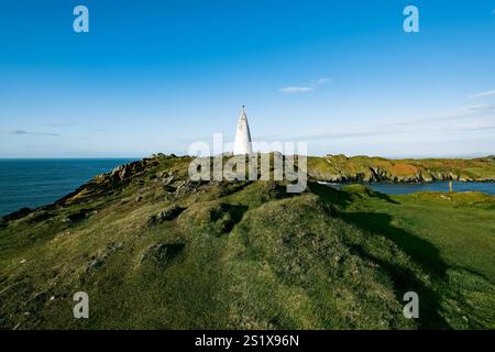 Der Leuchtturm steht an einem klaren, sonnigen Tag hoch vor dem blauen Himmel an der zerklüfteten Küste. Stockfoto