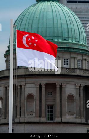 Die Kuppel der National Gallery of Singapore (ehemals Supreme Court) erhebt sich hinter der Nationalflagge Singapurs Stockfoto