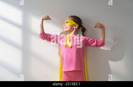 Weltkinderkrebstag. Mädchen im Superhelden Kostüm mit goldenem Band. Stockfoto