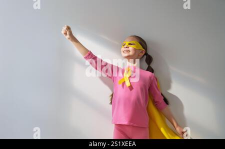 Weltkinderkrebstag. Mädchen im Superhelden Kostüm mit goldenem Band. Stockfoto