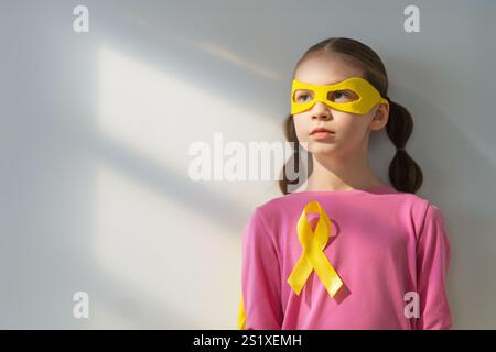 Weltkinderkrebstag. Mädchen im Superhelden Kostüm mit goldenem Band. Stockfoto