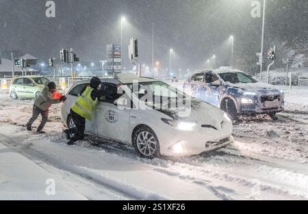 Leute helfen, Autos im Schnee in Leeds, Yorkshire, zu schieben. Starker nächtlicher Schnee sorgt für Störungen in ganz Großbritannien, da der Kaltstart ins neue Jahr anhält. Bilddatum: Sonntag, 5. Januar 2025. Stockfoto