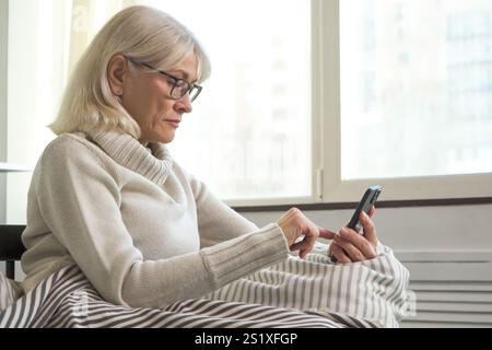 Ältere Frau, die ihr Smartphone zu Hause benutzt, besorgt ist Stockfoto