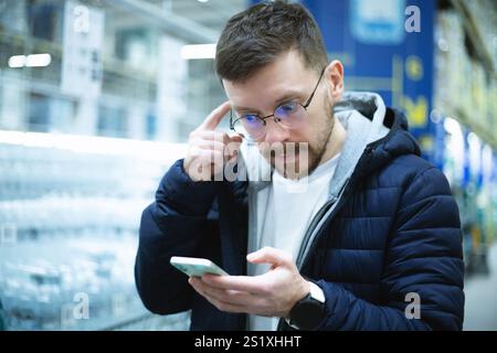 Ein überraschter und schockierter Kerl, der auf das Telefon schaut Stockfoto