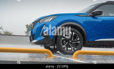 Blue Peugeot 2008 bei starkem Regen. Nahaufnahme der linken vorderen Ecke der kompakten französischen Crossover bei Regenwetter. Stockfoto