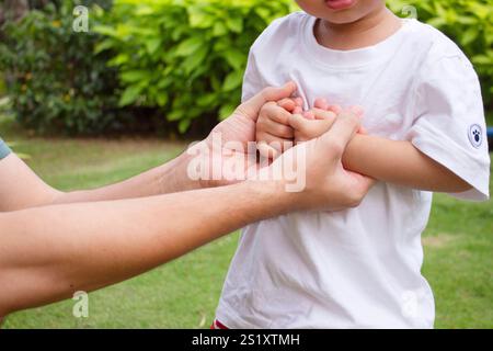 Asiatisches Baby Hände auf Vaterhand Stockfoto