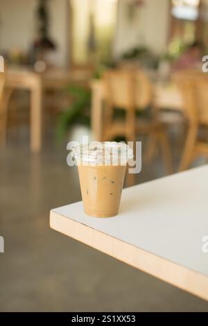 Ein erfrischender Eiskaffee steht auf einem Tisch in einem gemütlichen Café. Das perfekte Getränk zum Entspannen in einer warmen und einladenden Atmosphäre, ideal für den Sommer Stockfoto